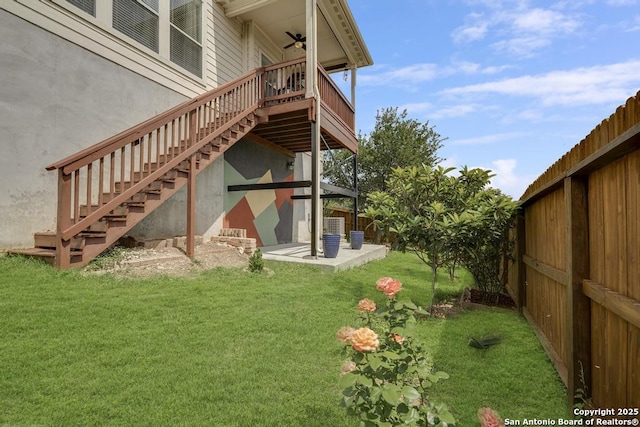 rear view of house featuring ceiling fan, a lawn, a deck, stairway, and fence