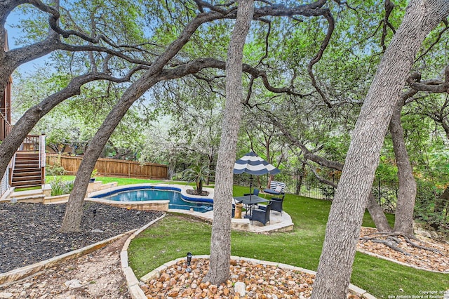 view of pool featuring a fenced backyard, a fenced in pool, a patio area, a lawn, and stairway