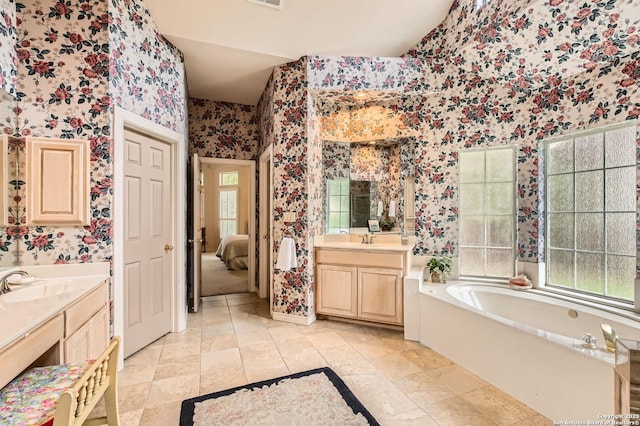 full bath with wallpapered walls, two vanities, a sink, and a bath