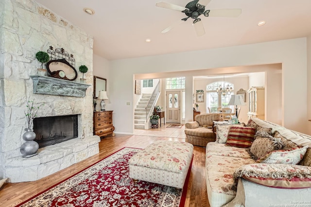living area with a fireplace, wood finished floors, stairway, ceiling fan with notable chandelier, and recessed lighting
