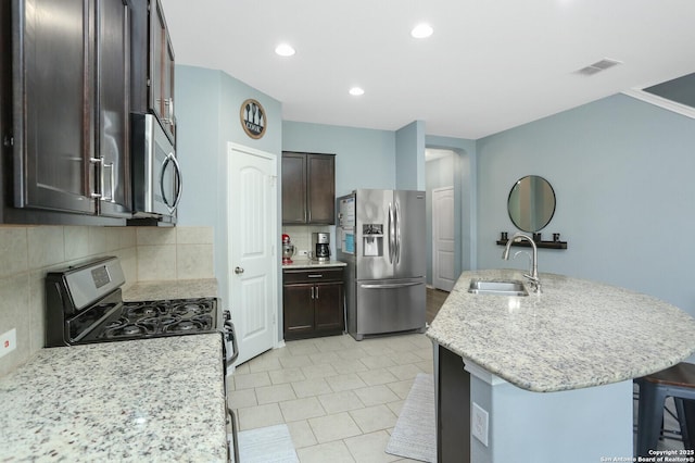 kitchen featuring visible vents, decorative backsplash, dark brown cabinets, a sink, and stainless steel appliances