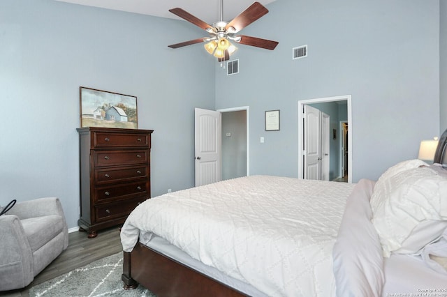 bedroom featuring visible vents, baseboards, wood finished floors, and high vaulted ceiling