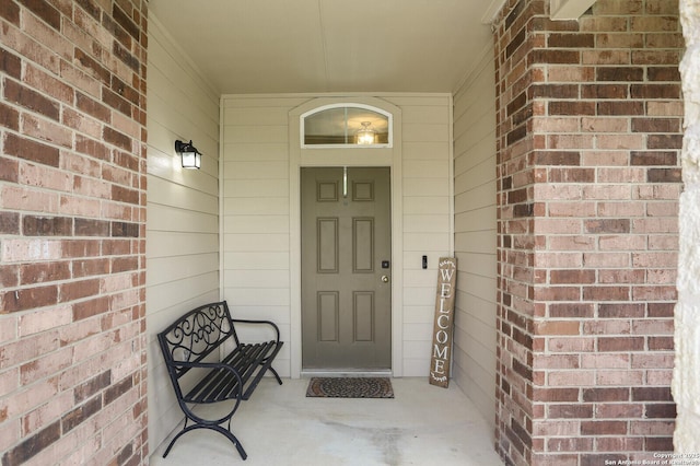 entrance to property featuring a porch and brick siding