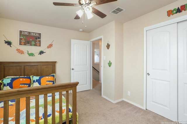 bedroom with a ceiling fan, light colored carpet, visible vents, baseboards, and a closet