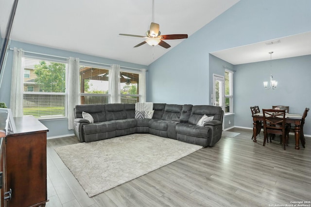living area with visible vents, a healthy amount of sunlight, light wood finished floors, and ceiling fan with notable chandelier