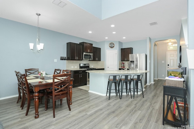 dining area with arched walkways, a chandelier, light wood-style flooring, recessed lighting, and visible vents