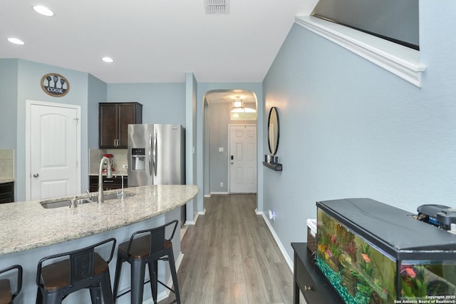 606 Sage Thrasher, San Antonio, TX 78253 - kitchen with dark brown cabinetry, a breakfast bar, a sink, arched walkways, and stainless steel refrigerator with ice dispenser