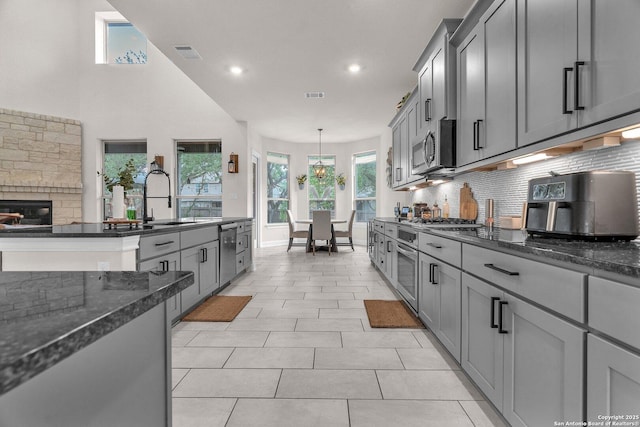 kitchen with appliances with stainless steel finishes, a stone fireplace, a sink, and visible vents