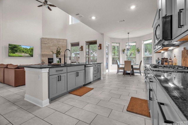 kitchen featuring a ceiling fan, visible vents, baseboards, open floor plan, and stainless steel appliances