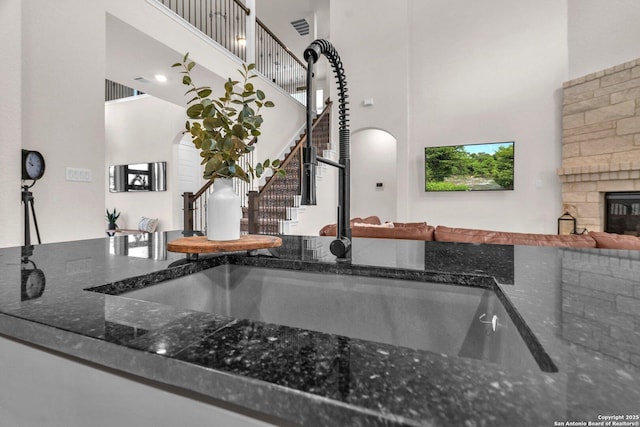 details featuring arched walkways, visible vents, a stone fireplace, and a sink