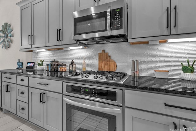 kitchen featuring appliances with stainless steel finishes, decorative backsplash, and dark stone countertops