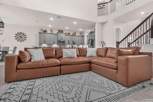 living area with visible vents, a towering ceiling, stairway, recessed lighting, and light tile patterned floors