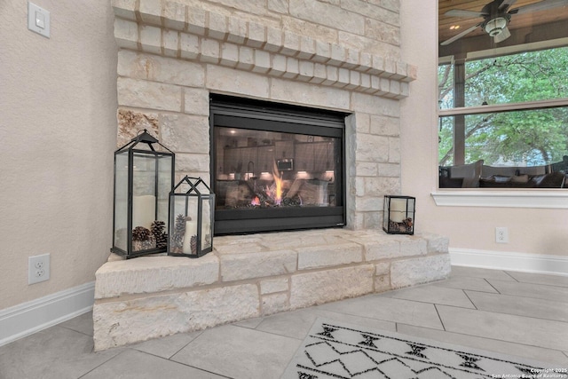 interior details with baseboards, a fireplace, and a ceiling fan