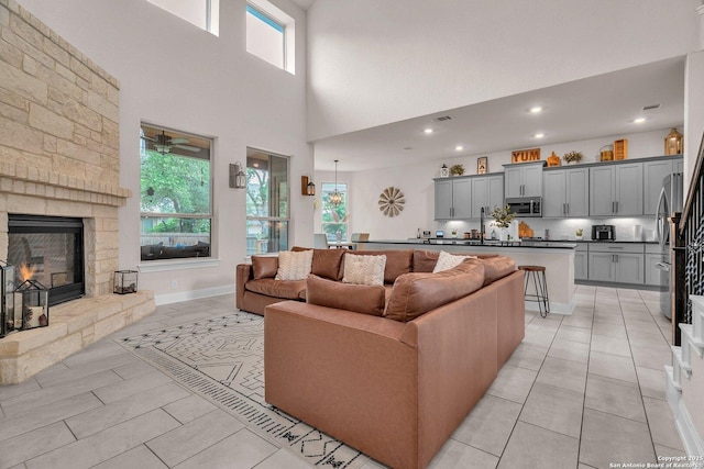 living room with light tile patterned floors, a high ceiling, a fireplace, and recessed lighting