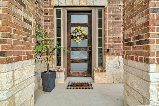 view of exterior entry with stone siding and brick siding