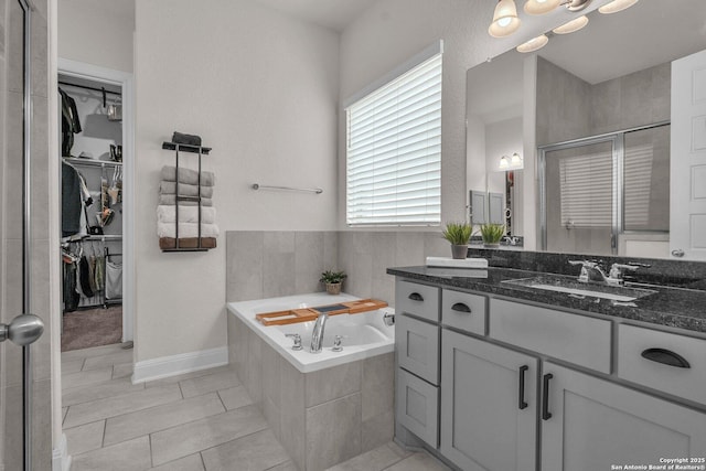 full bath featuring vanity, a bath, a spacious closet, and a shower stall