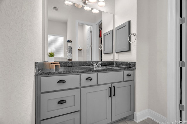bathroom with a textured wall, visible vents, and vanity