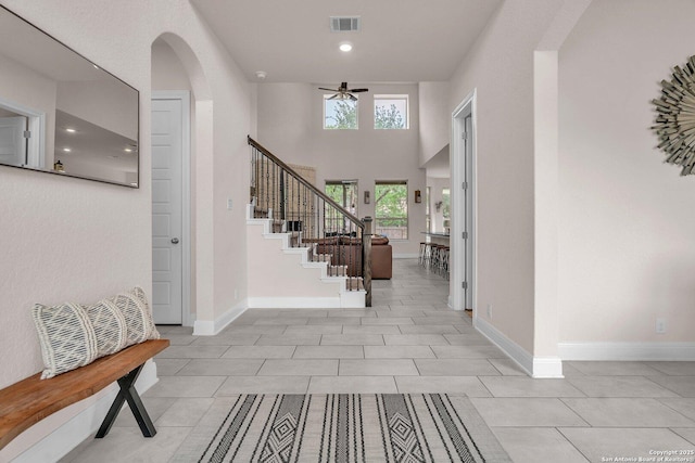 entrance foyer with a ceiling fan, baseboards, light tile patterned floors, visible vents, and stairway