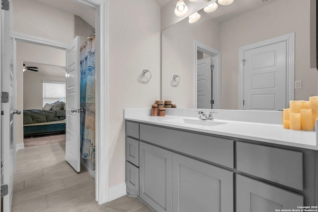 ensuite bathroom featuring vanity, a ceiling fan, baseboards, and ensuite bathroom