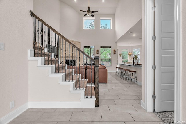 tiled foyer with a towering ceiling, baseboards, ceiling fan, stairway, and recessed lighting