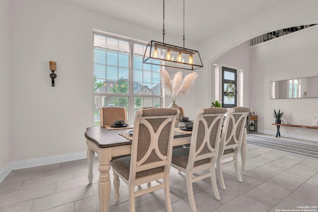 dining room featuring arched walkways, baseboards, and light tile patterned flooring