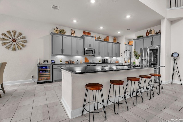 kitchen with gray cabinetry, appliances with stainless steel finishes, and beverage cooler