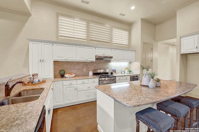 kitchen with visible vents, a breakfast bar area, under cabinet range hood, finished concrete floors, and a sink