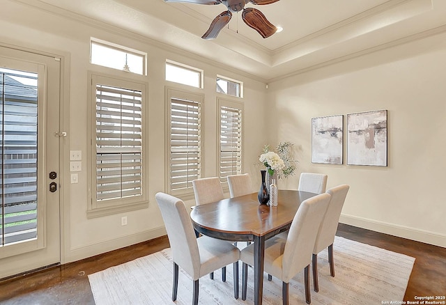 dining area featuring crown molding, baseboards, ceiling fan, and a tray ceiling