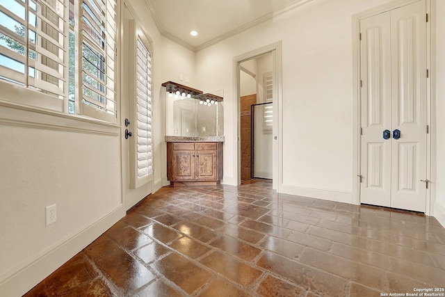 interior space with stone tile flooring, ornamental molding, a shower with door, vanity, and baseboards