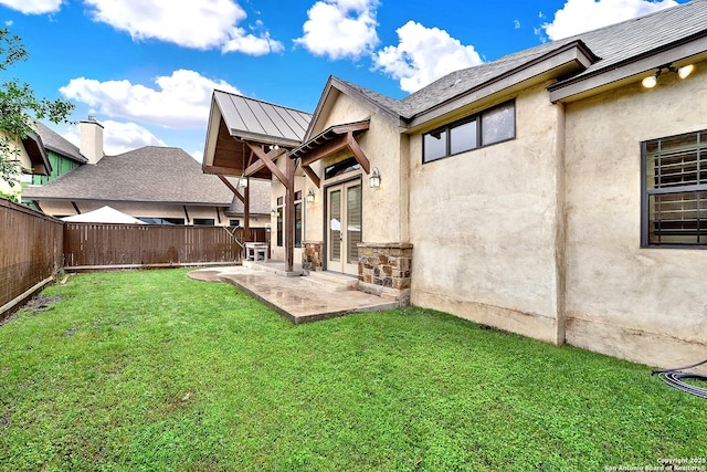 rear view of house with stone siding, a patio, a fenced backyard, stucco siding, and a yard