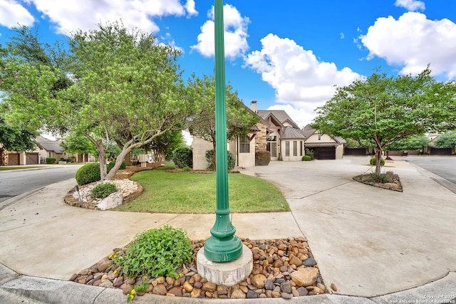 view of front of property with curved driveway, a chimney, and a front lawn