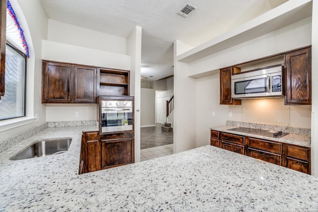 10210 Apricot Fld, San Antonio, TX 78245 - kitchen featuring open shelves, appliances with stainless steel finishes, dark brown cabinetry, a sink, and visible vents