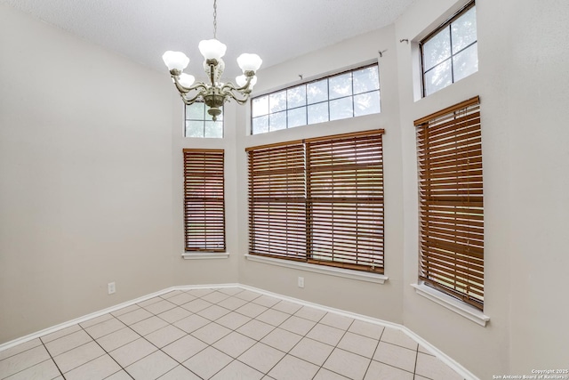 10210 Apricot Fld, San Antonio, TX 78245 - empty room with light tile patterned floors, baseboards, a wealth of natural light, and a notable chandelier