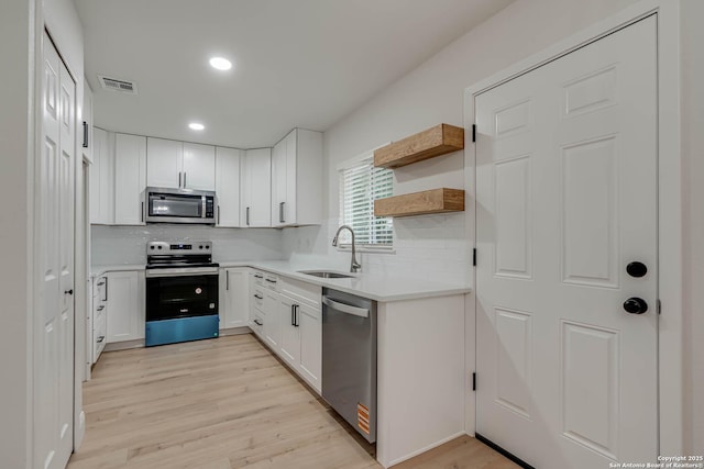kitchen featuring visible vents, light wood-type flooring, a sink, appliances with stainless steel finishes, and backsplash
