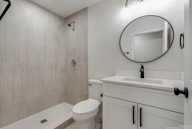 bathroom with vanity, toilet, and tiled shower