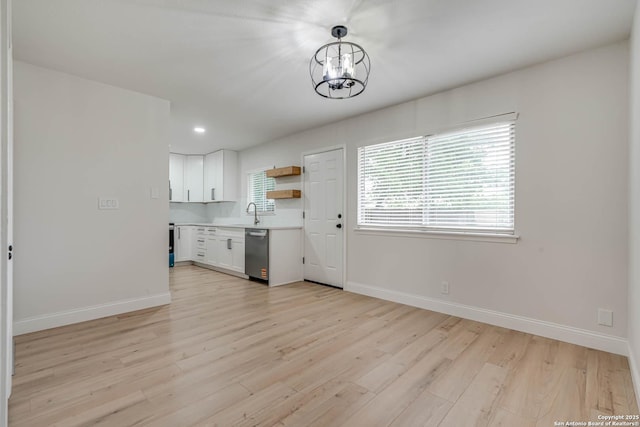 kitchen with open shelves, stainless steel dishwasher, light wood finished floors, a chandelier, and white cabinetry