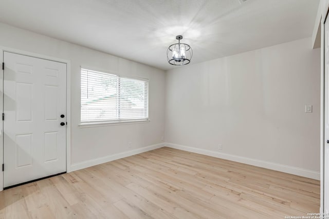 unfurnished dining area with an inviting chandelier, baseboards, and light wood-type flooring