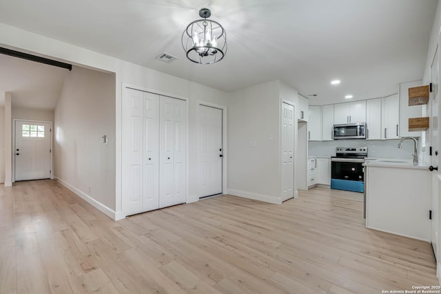 kitchen featuring visible vents, a sink, light wood finished floors, and appliances with stainless steel finishes