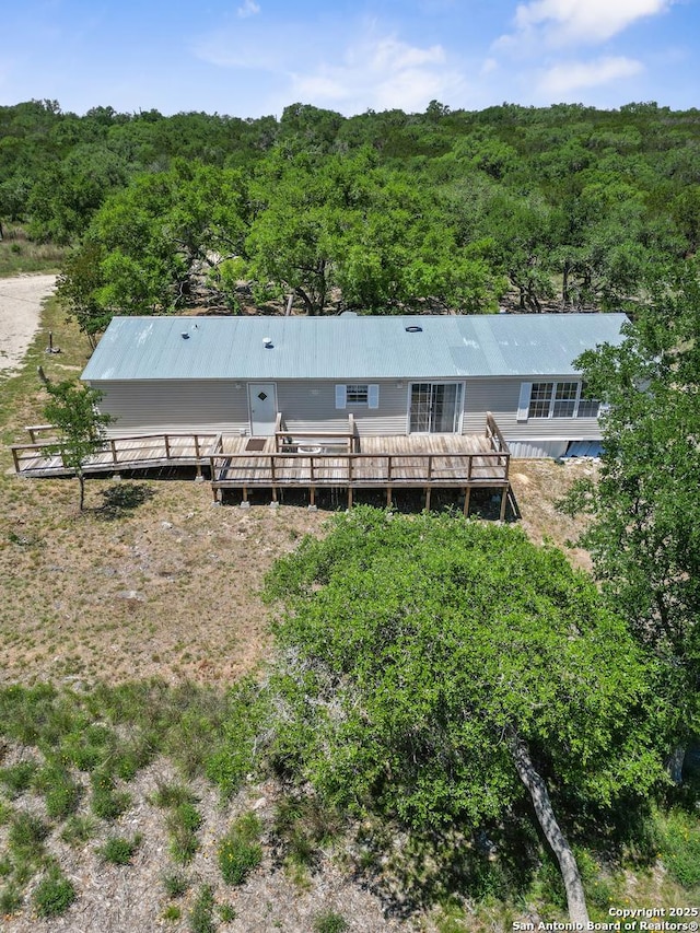 back of property with a wooden deck and a wooded view