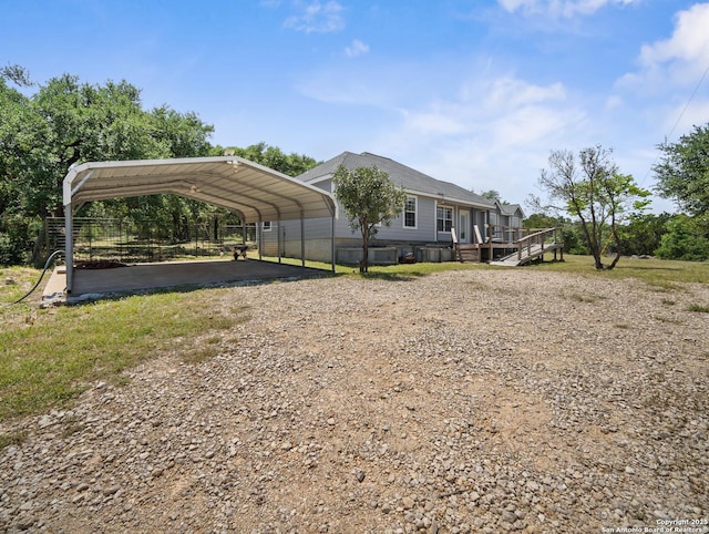 exterior space with driveway, a wooden deck, and a carport
