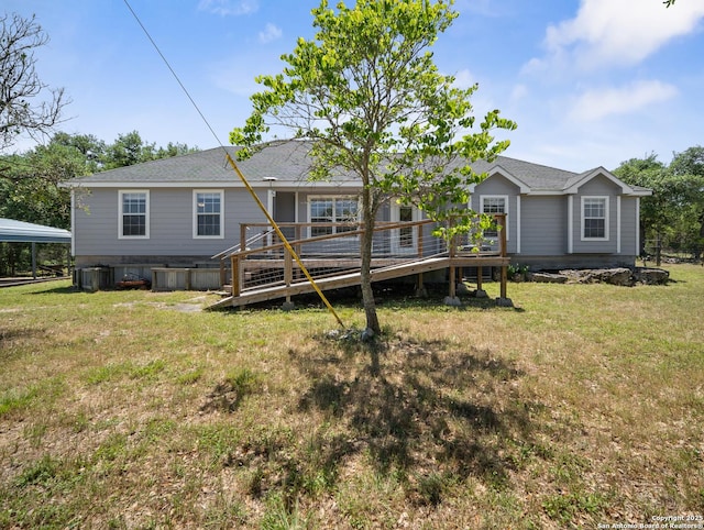 rear view of house with a lawn, a deck, and a shingled roof