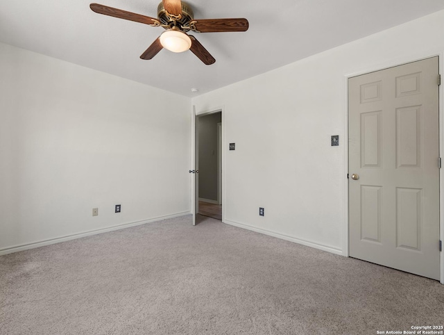 empty room featuring ceiling fan, light colored carpet, and baseboards