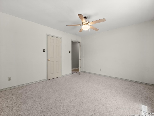spare room featuring baseboards, ceiling fan, and light carpet