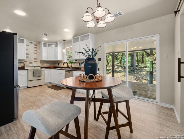 kitchen with visible vents, dark countertops, light wood finished floors, backsplash, and stainless steel appliances