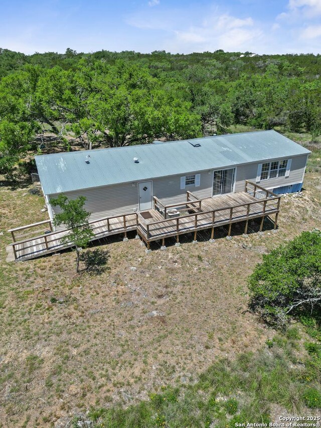 back of house with a wooden deck, metal roof, and a forest view