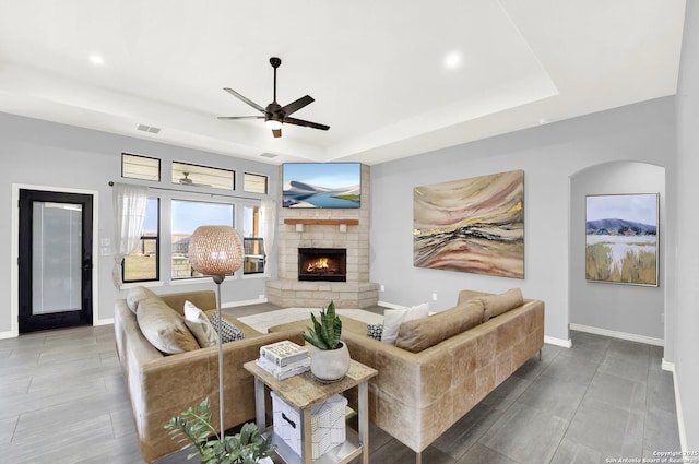 living room with ceiling fan, baseboards, and a raised ceiling