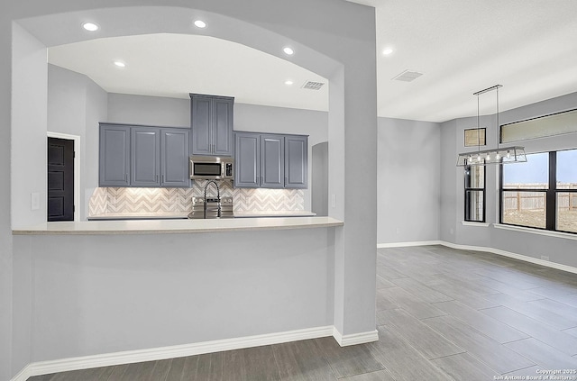 kitchen featuring visible vents, appliances with stainless steel finishes, light countertops, baseboards, and a peninsula