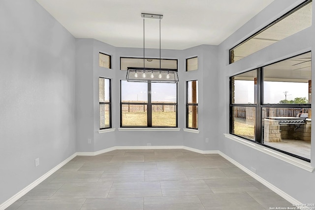 unfurnished dining area featuring baseboards, tile patterned flooring, and a wealth of natural light