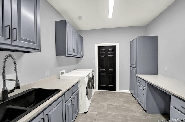 washroom featuring cabinet space, a sink, baseboards, visible vents, and washer and clothes dryer