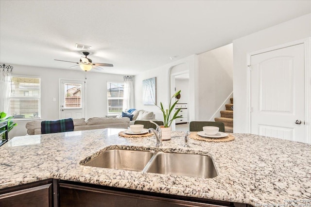 2927 Lindenwood, San Antonio, TX 78245 - kitchen with visible vents, dark brown cabinetry, light stone countertops, open floor plan, and a ceiling fan